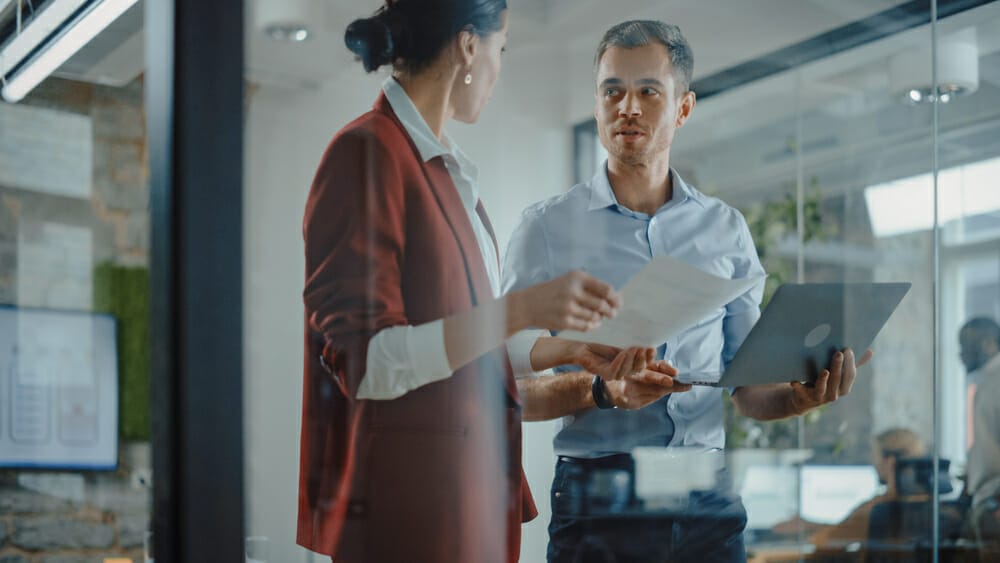 Two colleagues discussing layoffs in an office setting.